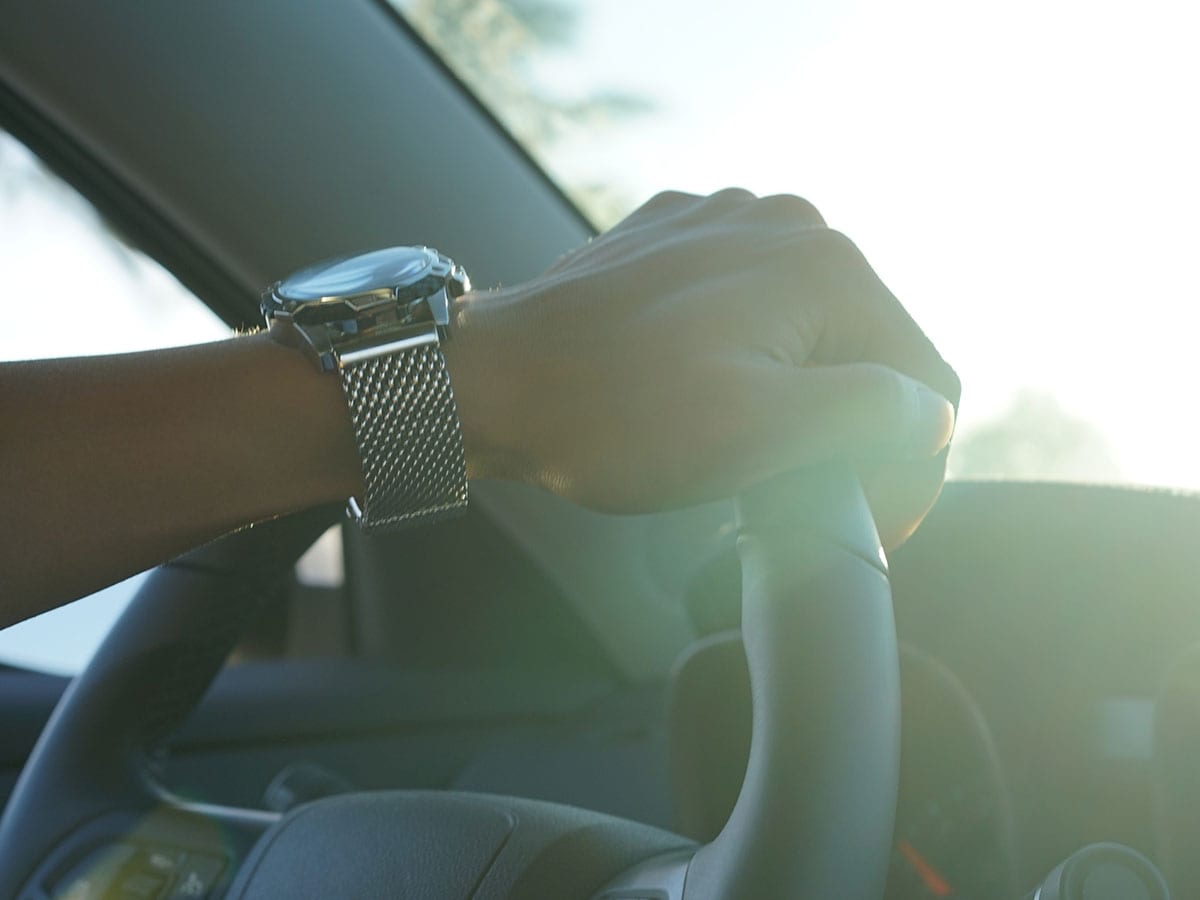 Hand on steering wheel, wearing watch